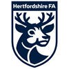 **Alt Text:** The logo for the Hertfordshire FA, a blue shield, with a deer logo on it